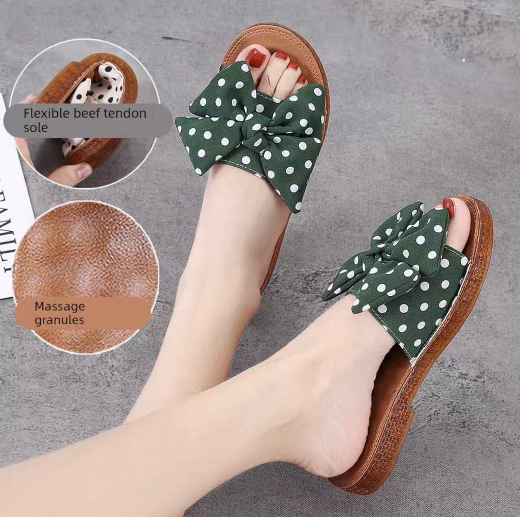 Green polka dot sandals with bow details on a gray surface