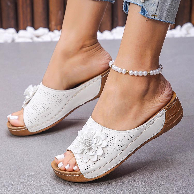White sandals with floral designs on a neutral background