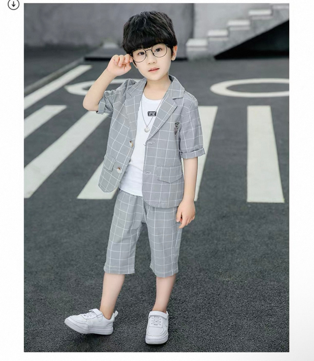 Child wearing a gray checkered suit standing on a road with white markings.