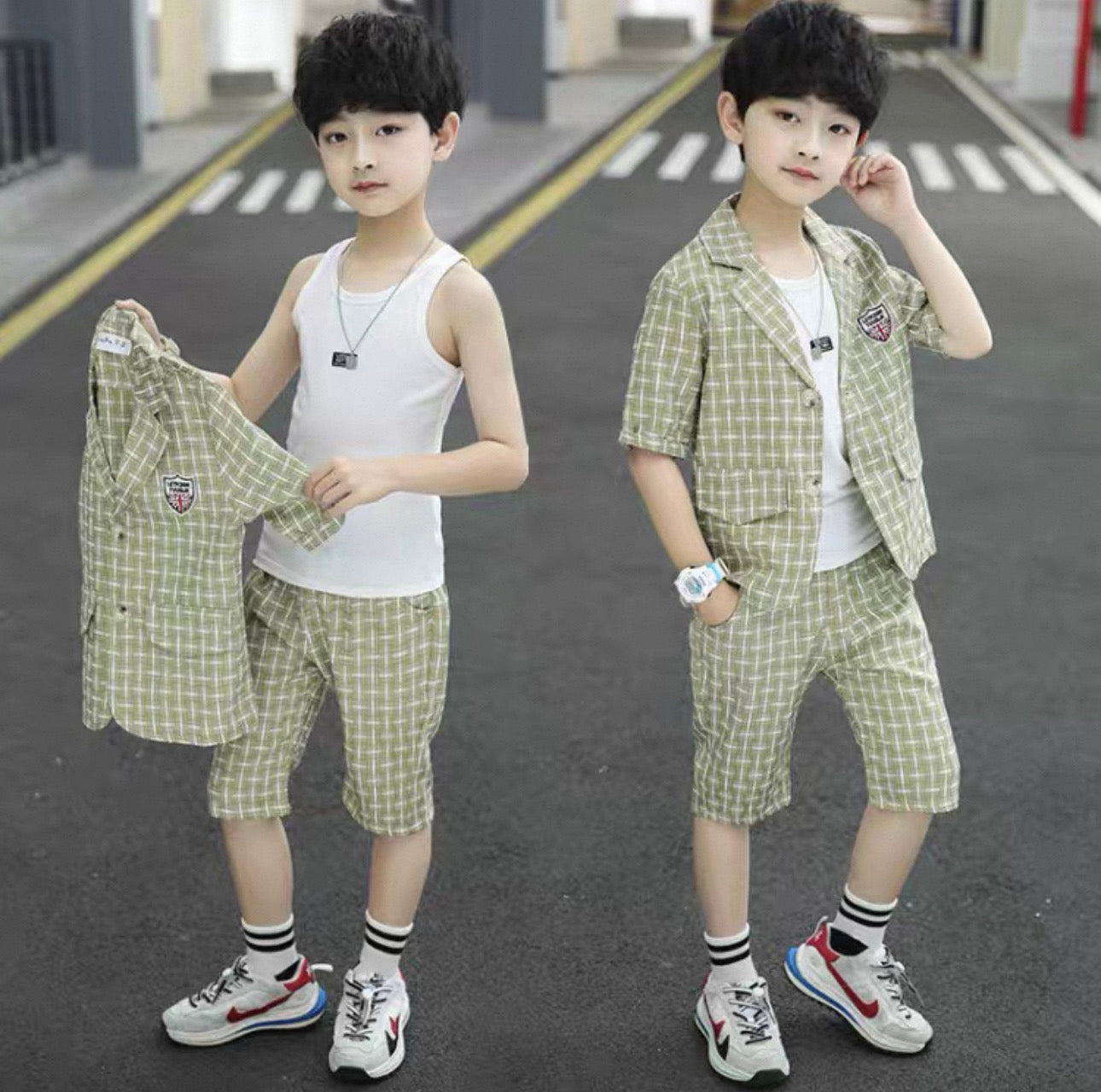 Two children wearing matching green checkered outfits on a road.