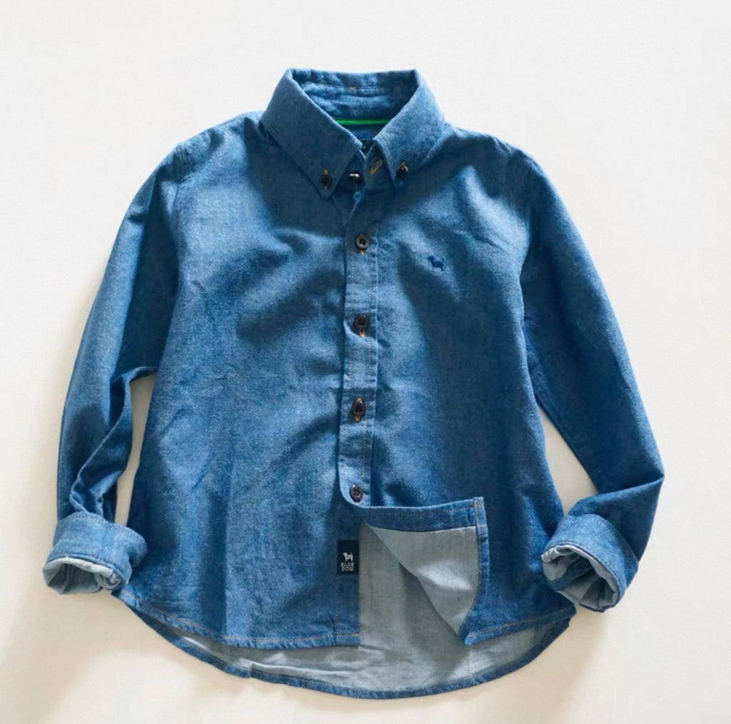Blue denim shirt with rolled-up sleeves on a light beige background