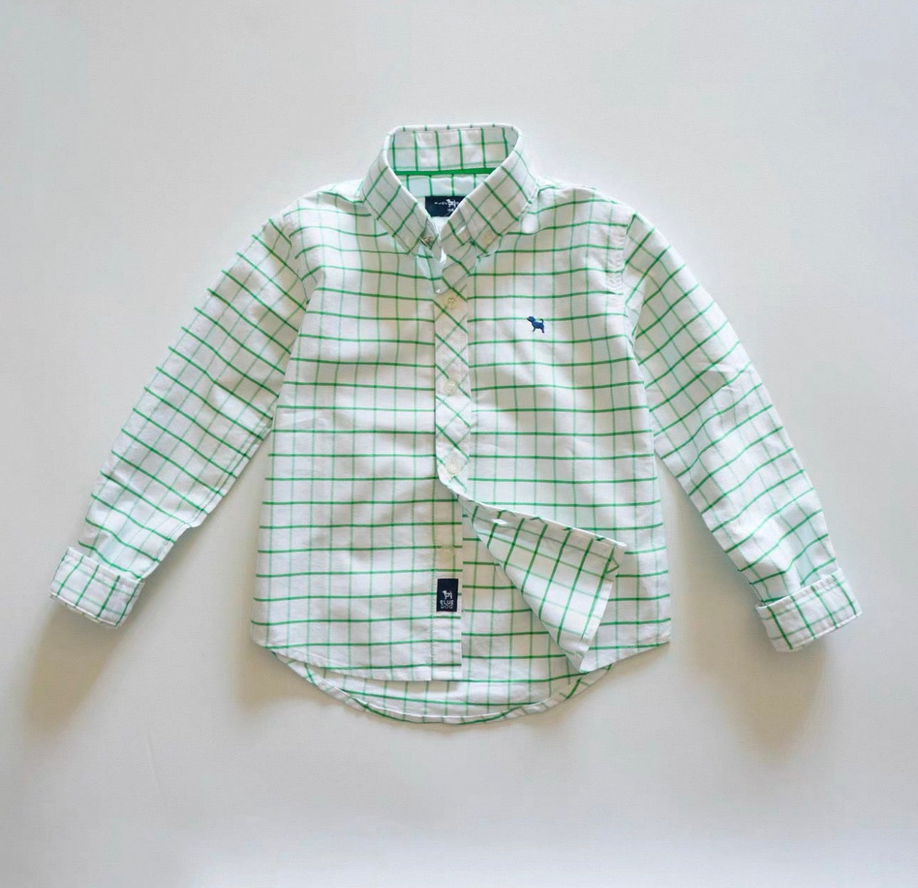 Green and white checkered shirt with a logo on a light gray background