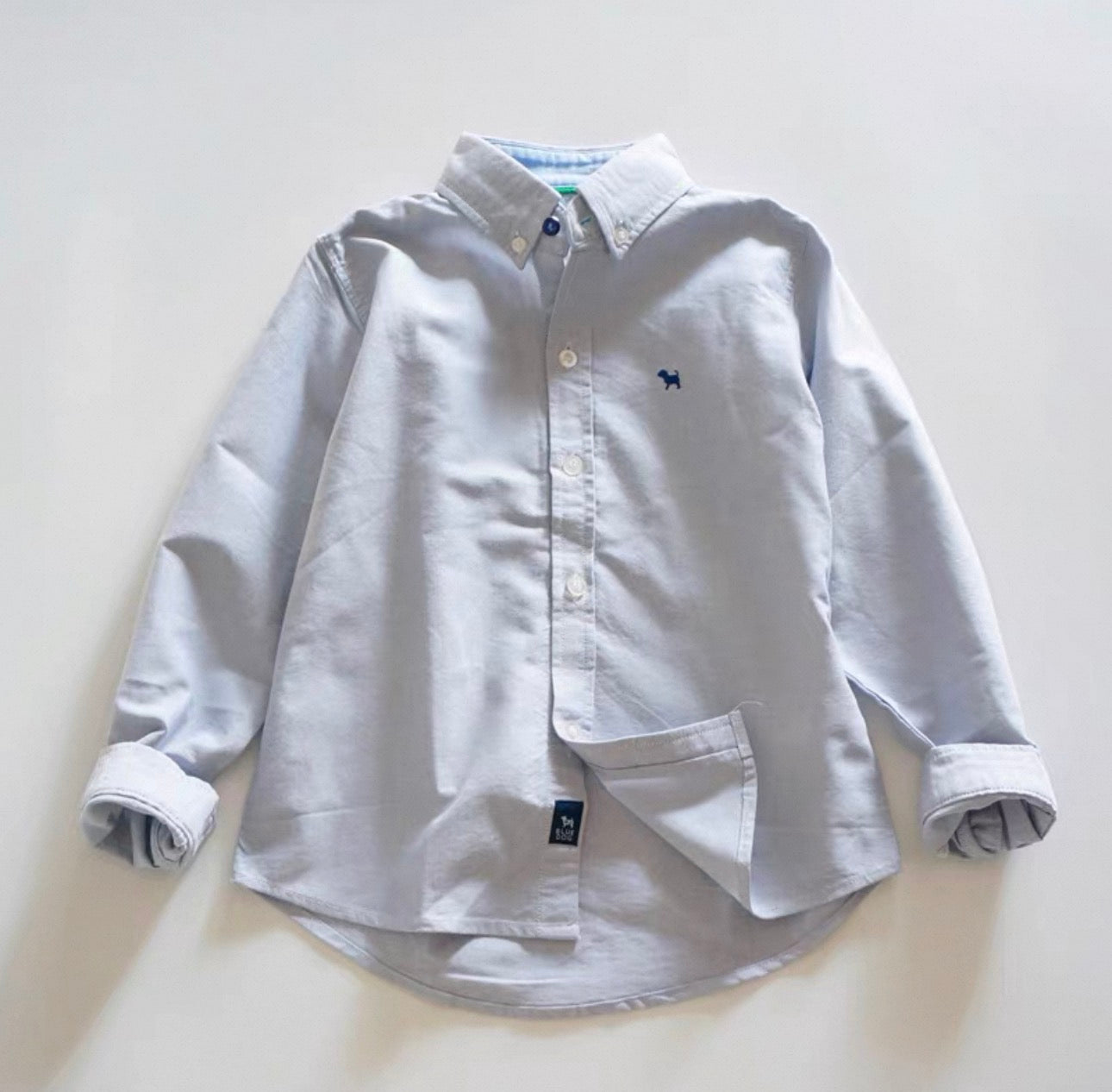 Light blue button-up shirt with rolled sleeves on a white background