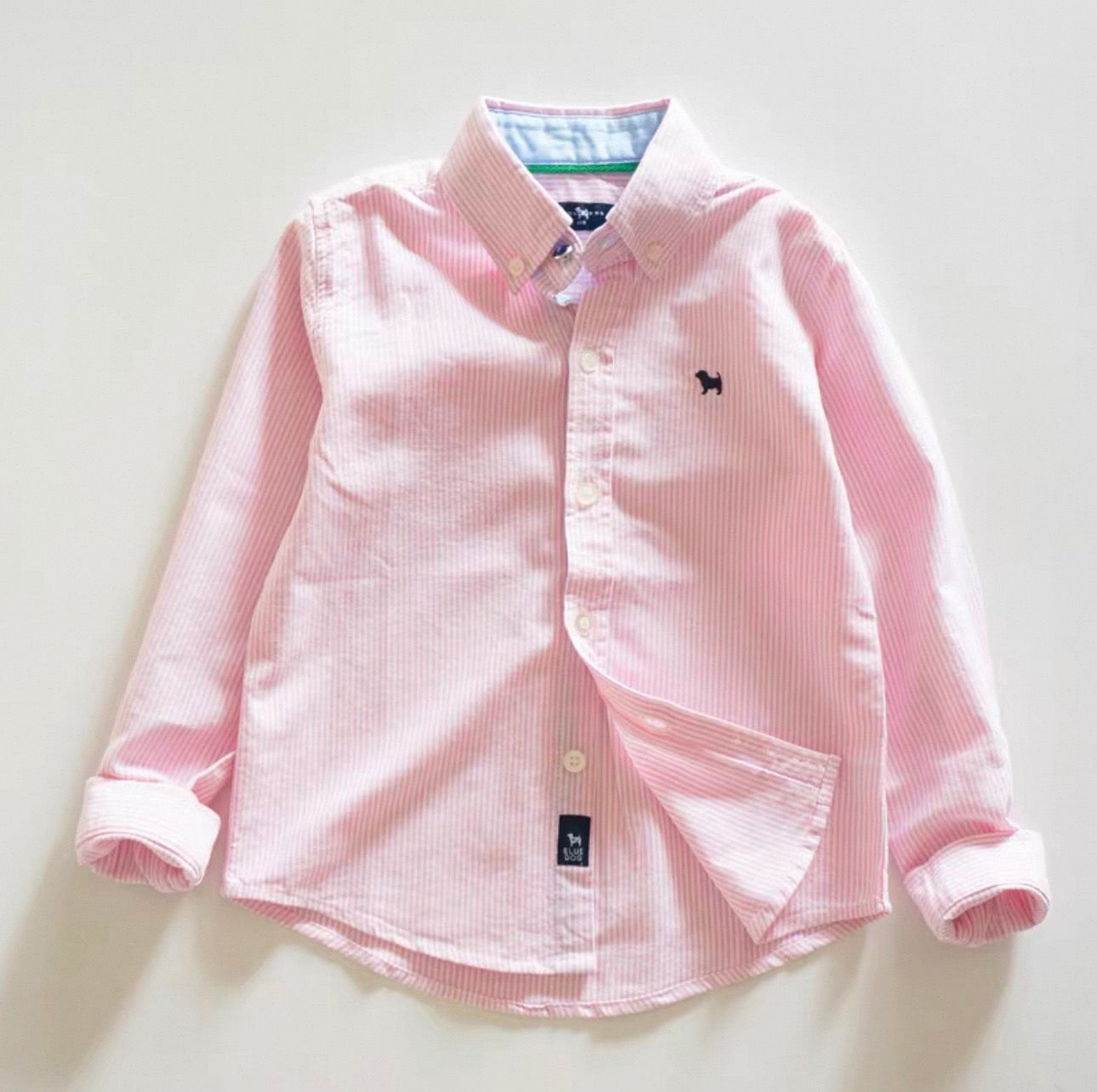 Pink striped shirt with a small logo on a light background