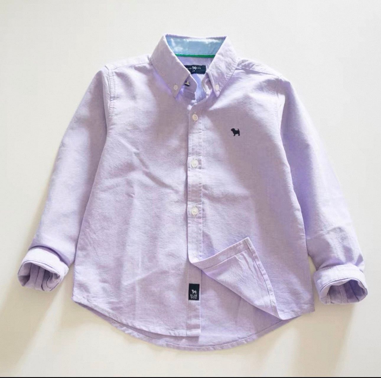 Light purple button-up shirt with a small logo on a light beige background
