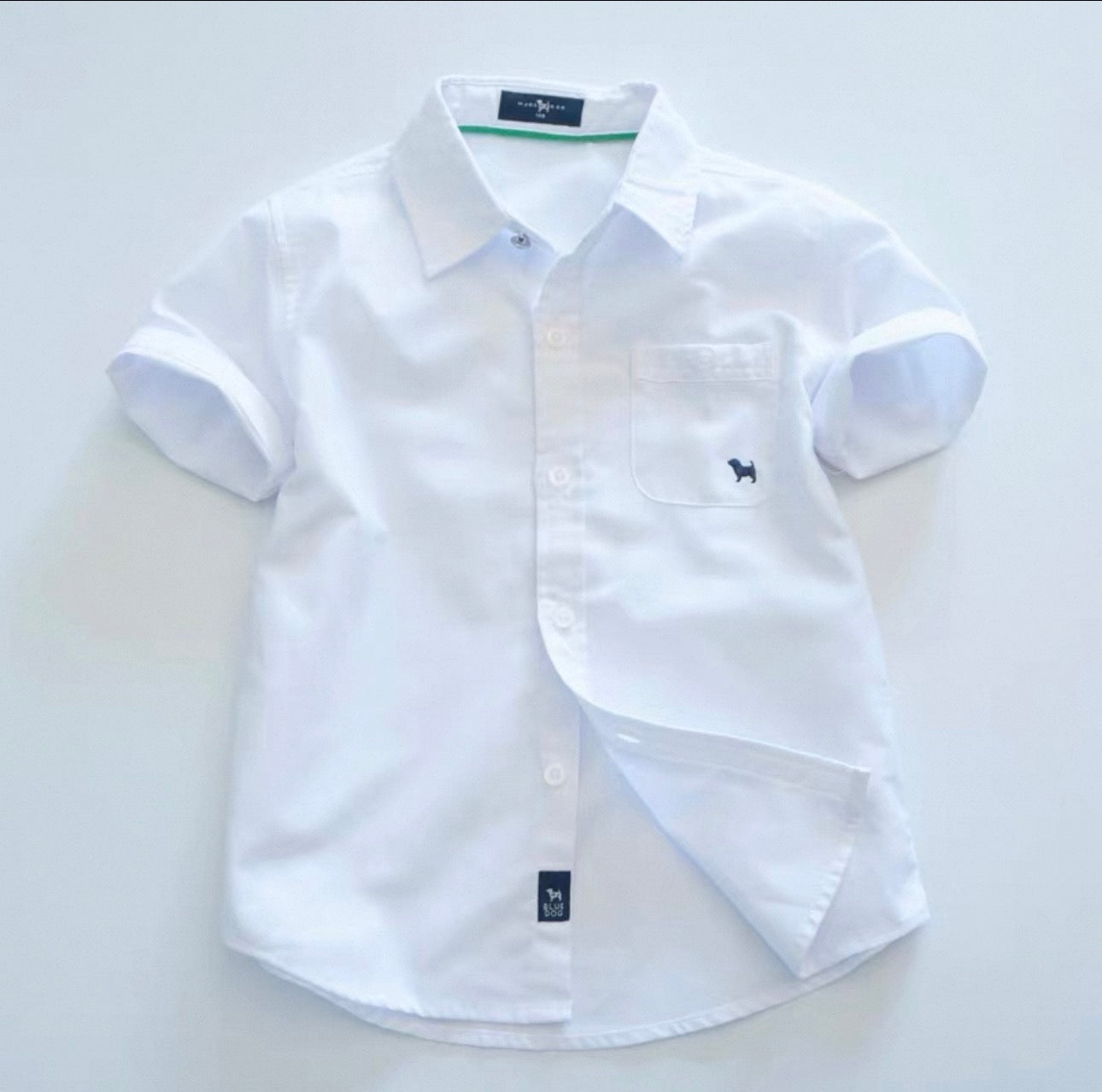White short-sleeve shirt with rolled-up sleeves on a light gray background