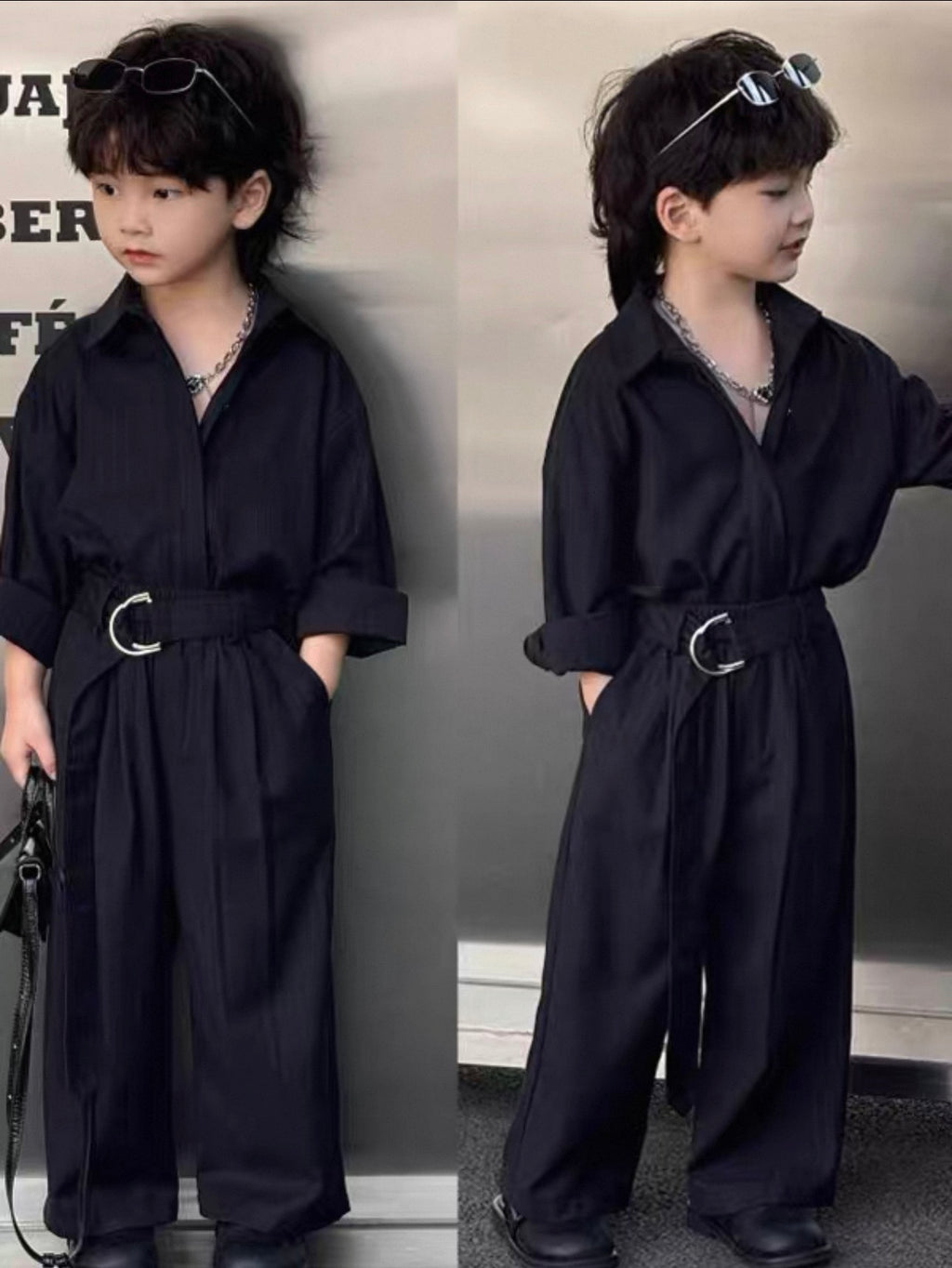 Child wearing a dark shirt and pants suit with a belt in front of a gray background