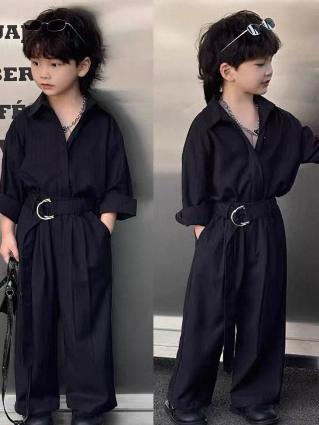 Child wearing a dark shirt and pants suit with a belt in front of a gray background