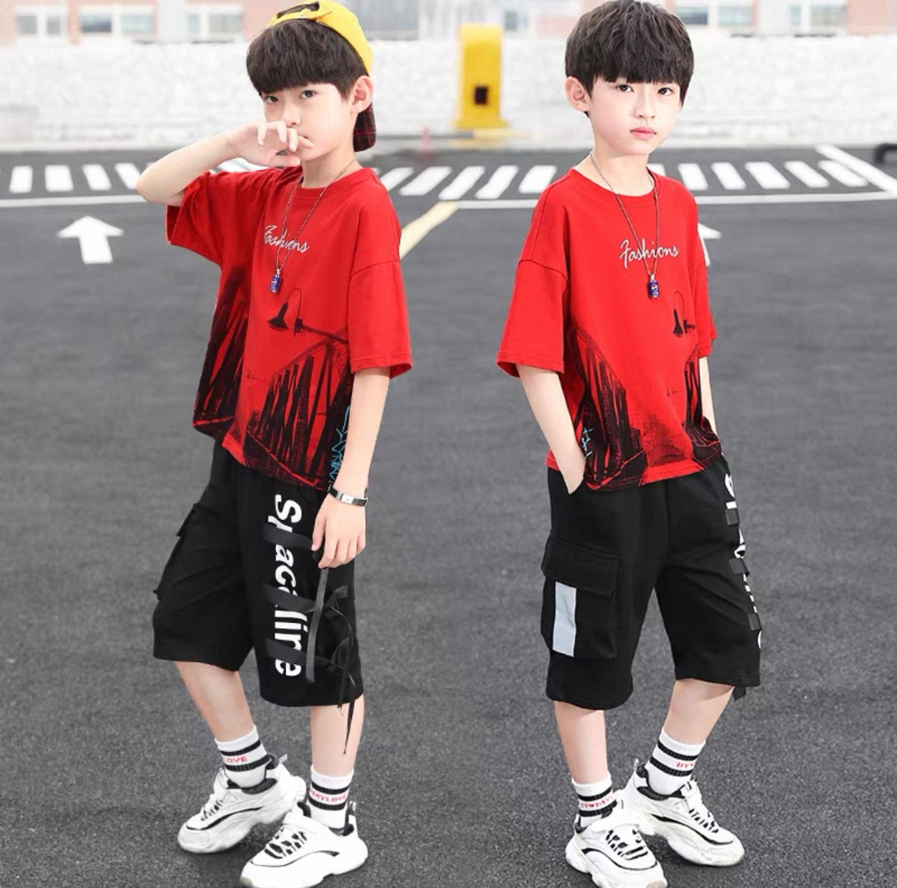 Two children wearing matching red t-shirts and black shorts on a street.