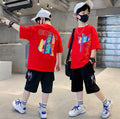 Two children wearing red t-shirts with colorful designs, standing in a modern indoor setting.