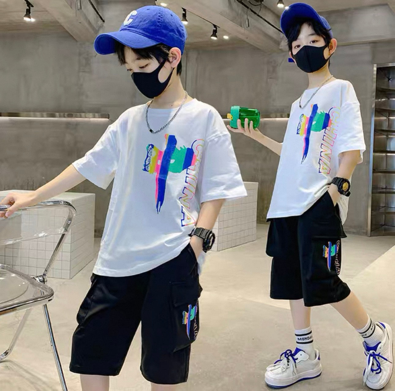 Two children wearing matching outfits with white t-shirts and black shorts in a modern indoor setting.