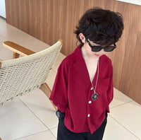 Child wearing a red shirt and sunglasses indoors