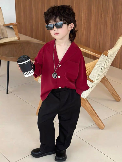 Child wearing a red shirt and black pants, holding a coffee cup indoors.