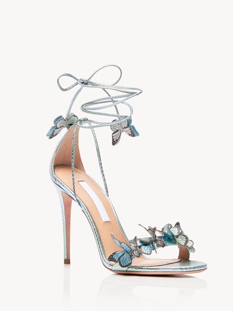 Silver stiletto high heel sandal with ankle wrap strap and decorative butterfly accents.