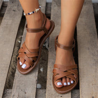 Brown sandals worn on feet with a neutral background