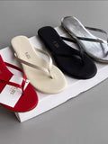 Four pairs of flip-flops in red, white, black, and silver on a gray surface.