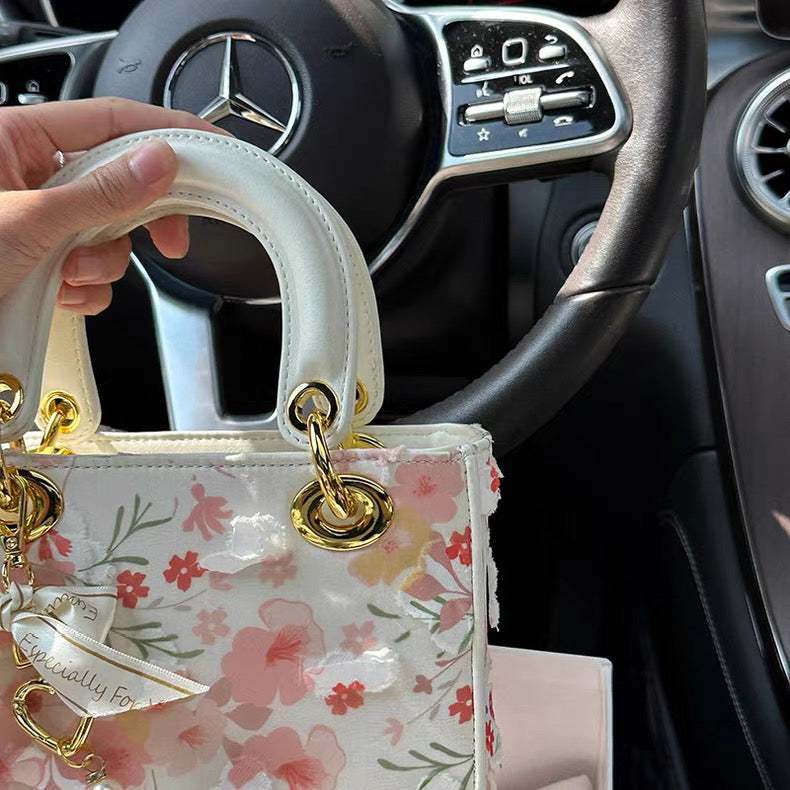 Floral handbag held in front of a Mercedes-Benz steering wheel