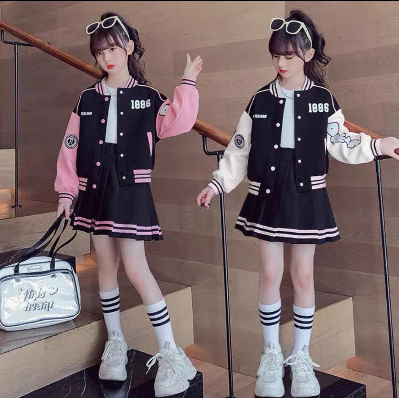 Two girls in matching black and white varsity jackets with pink and white accents, standing on a staircase.