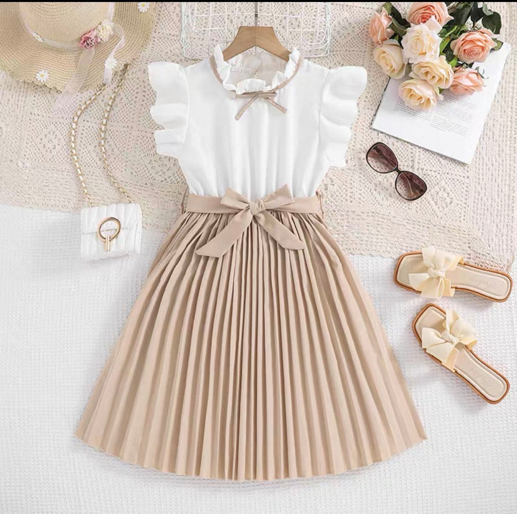 White top with beige pleated skirt on a textured surface with accessories.