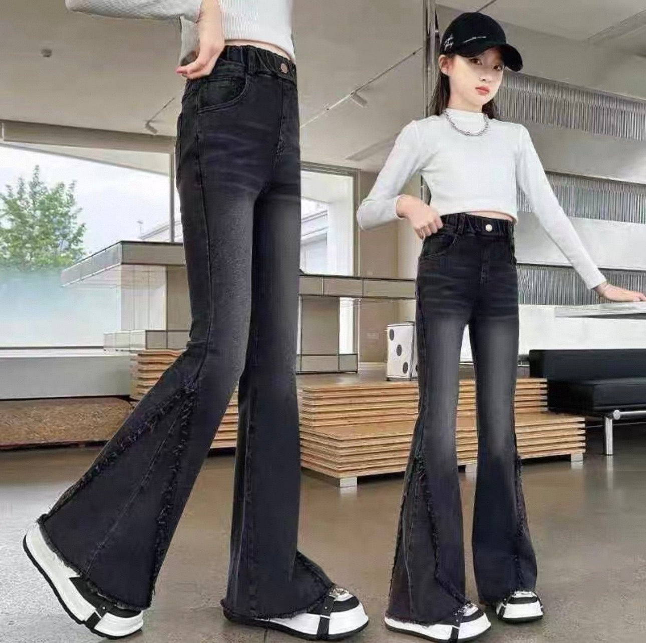 Two people wearing black flared jeans in an indoor setting.