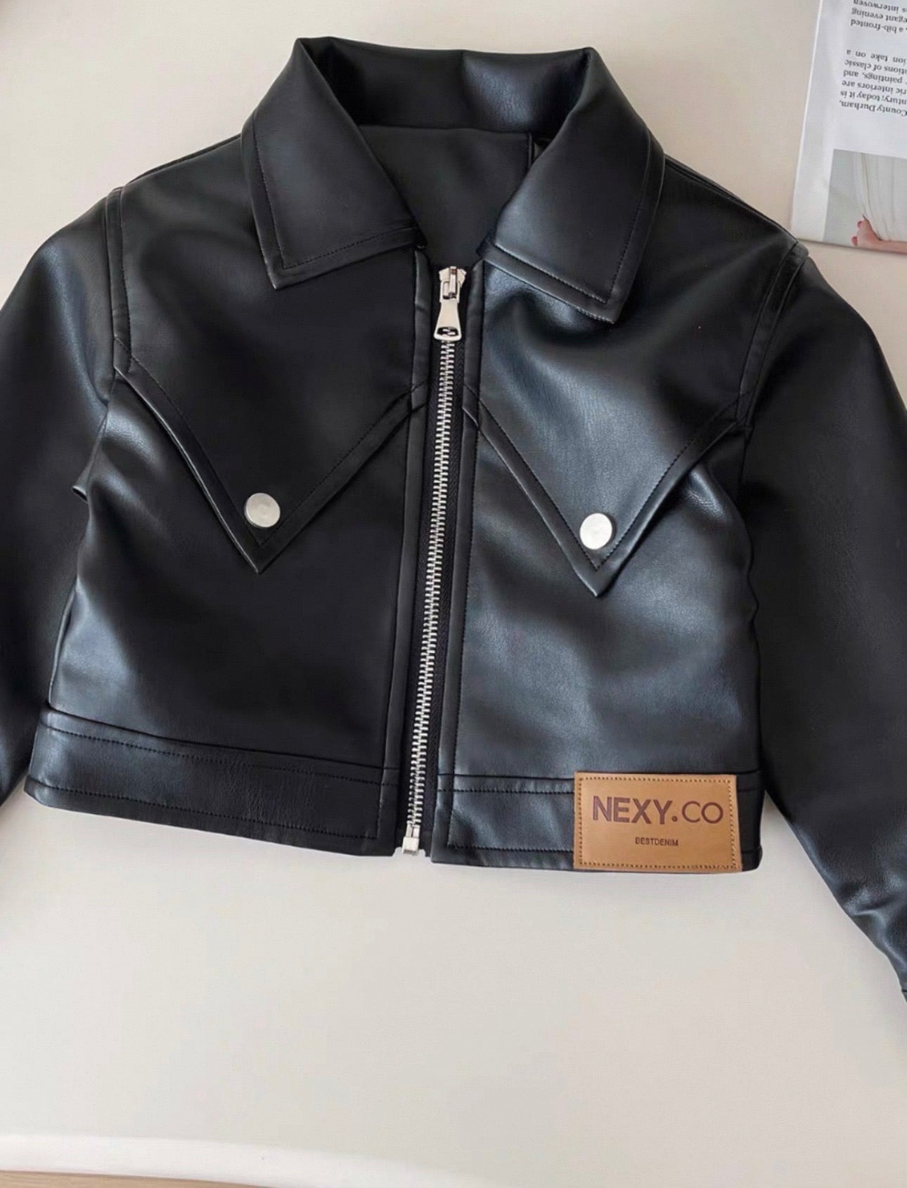 Black leather jacket with a brand label on a mannequin against a neutral background