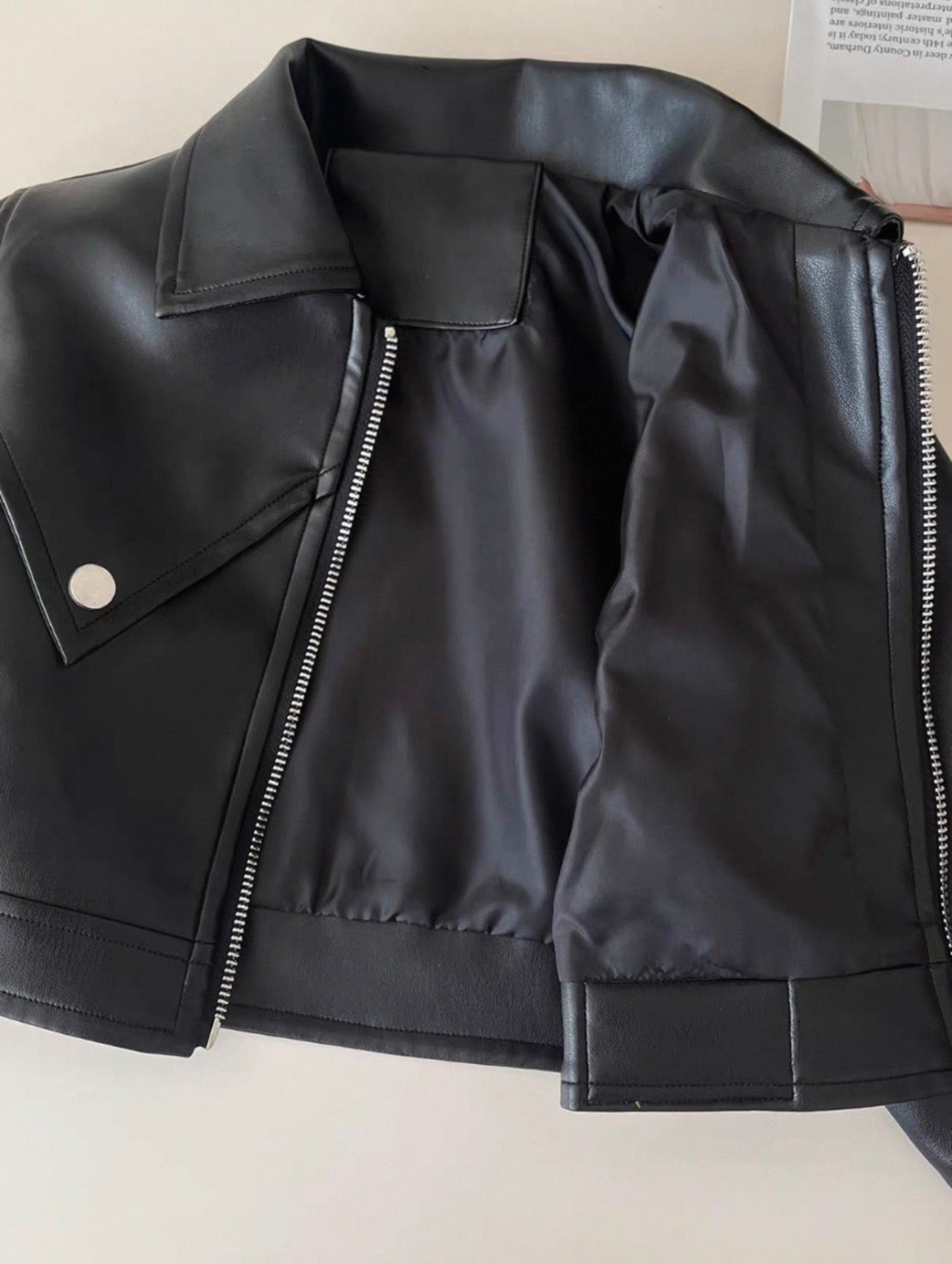 Black leather jacket with a zipper on a light background