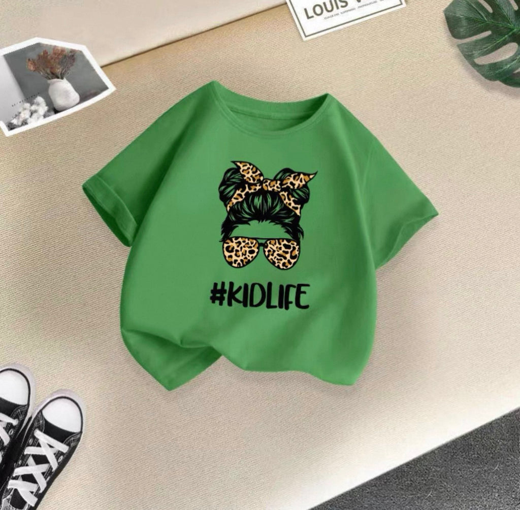 Green t-shirt with '#KIDLIFE' design on a beige surface