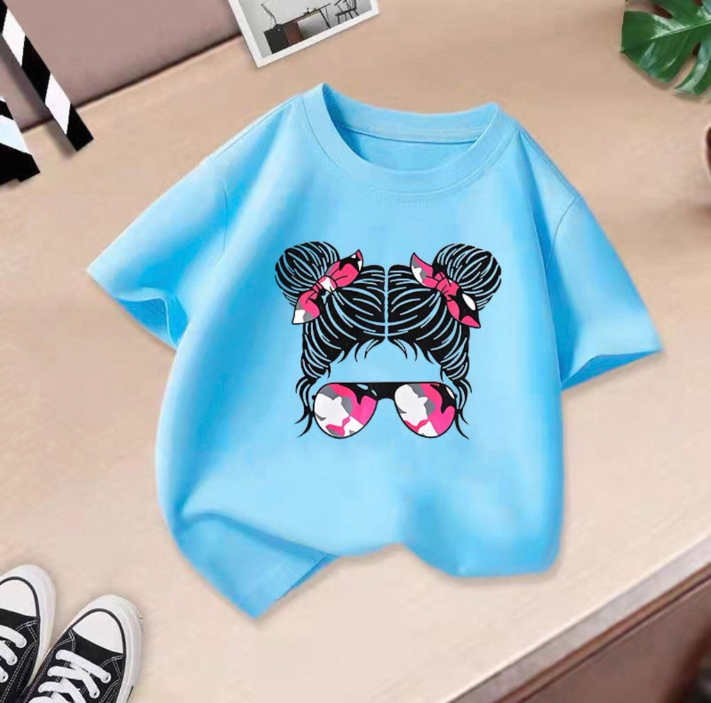 Light blue t-shirt with a graphic design of two buns with bows and sunglasses on a beige surface.