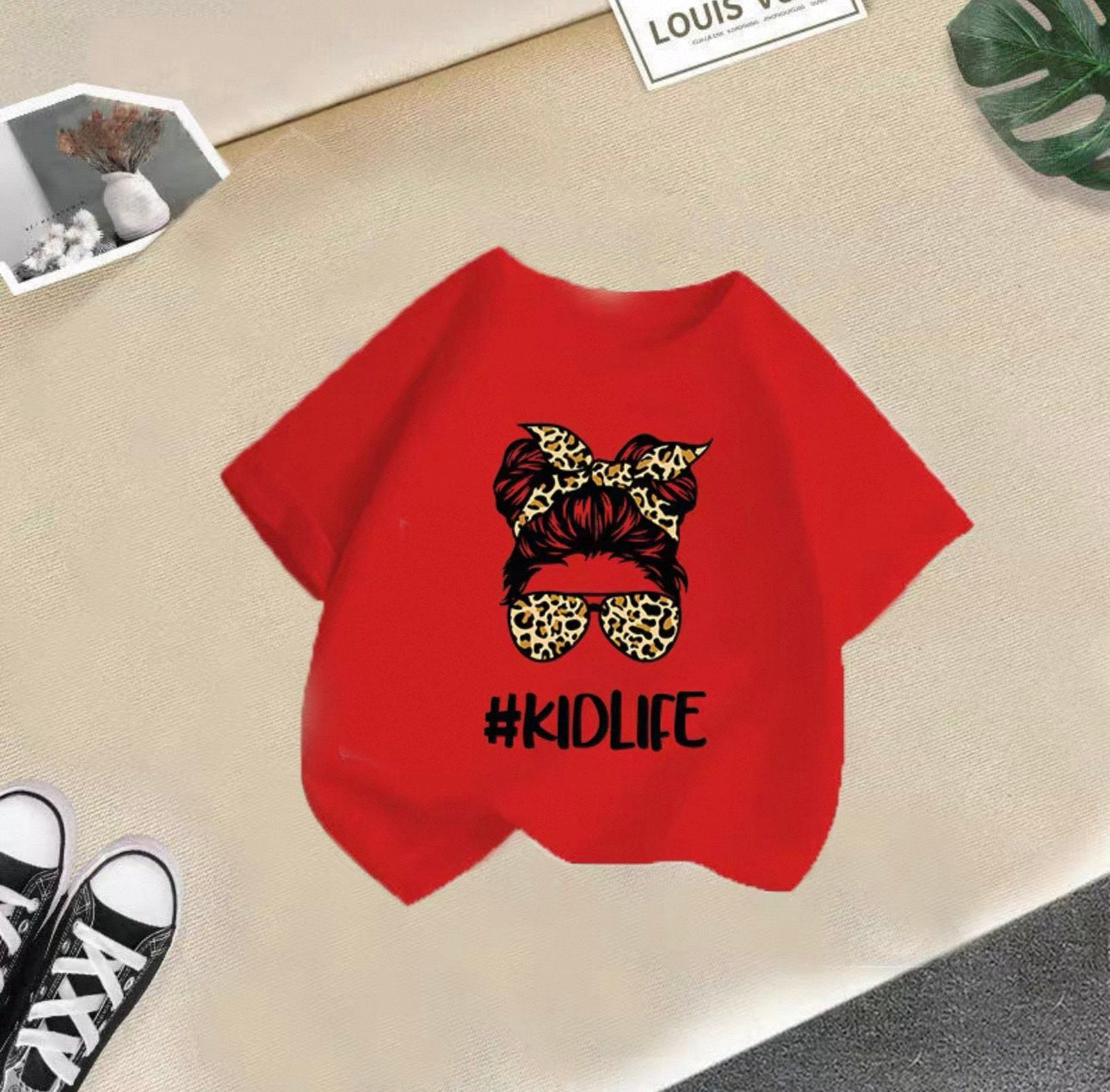 Red t-shirt with '#KIDLIFE' design on a beige surface