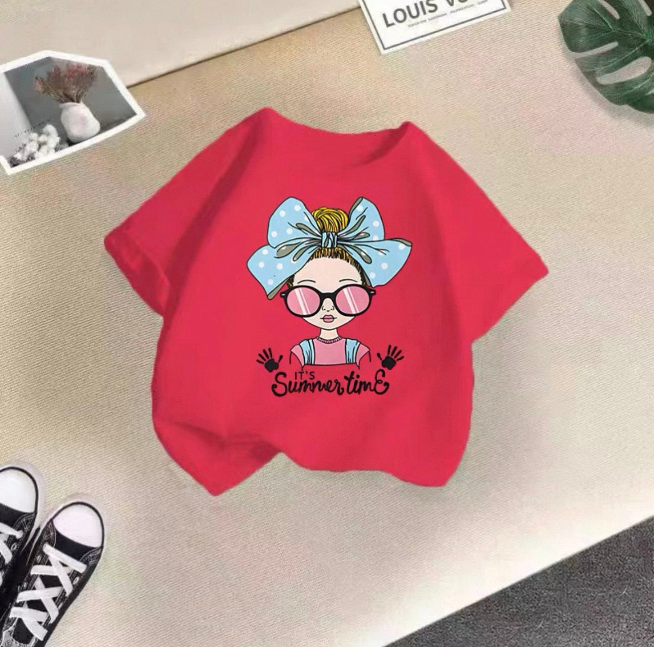 Red sweatshirt with a cartoon character and 'it's Summertime' text on a beige surface.