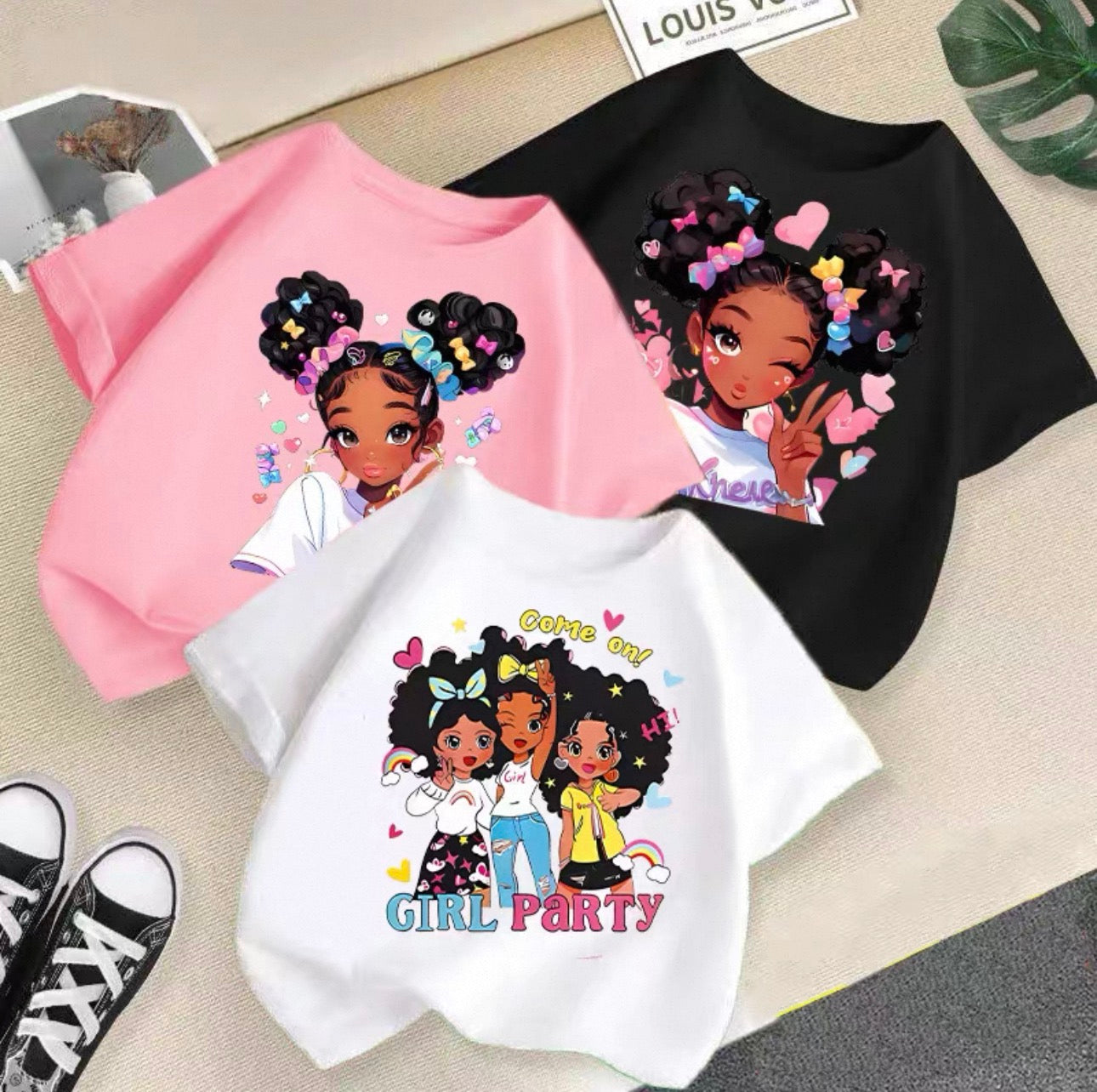Three t-shirts with cartoon characters and text on a surface.