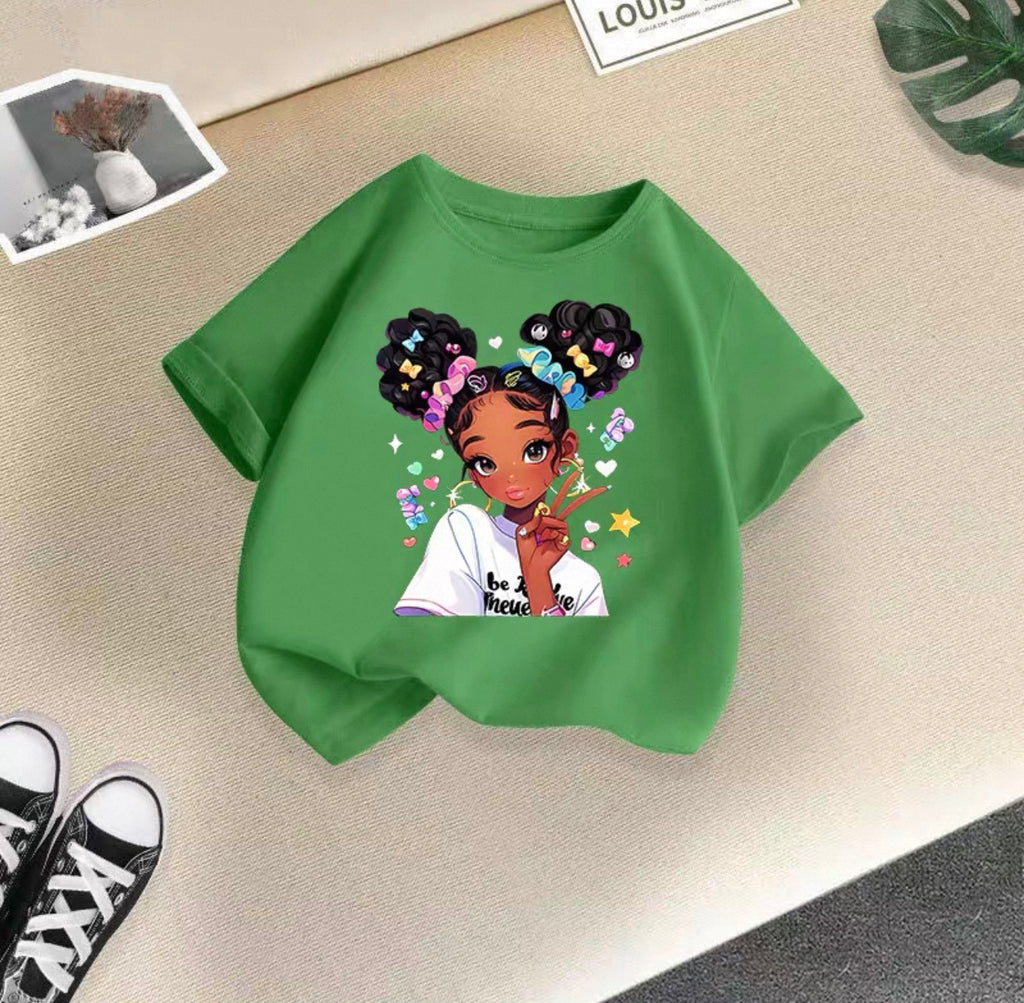 Green t-shirt with a graphic of a girl with braids and colorful letters on a beige surface.