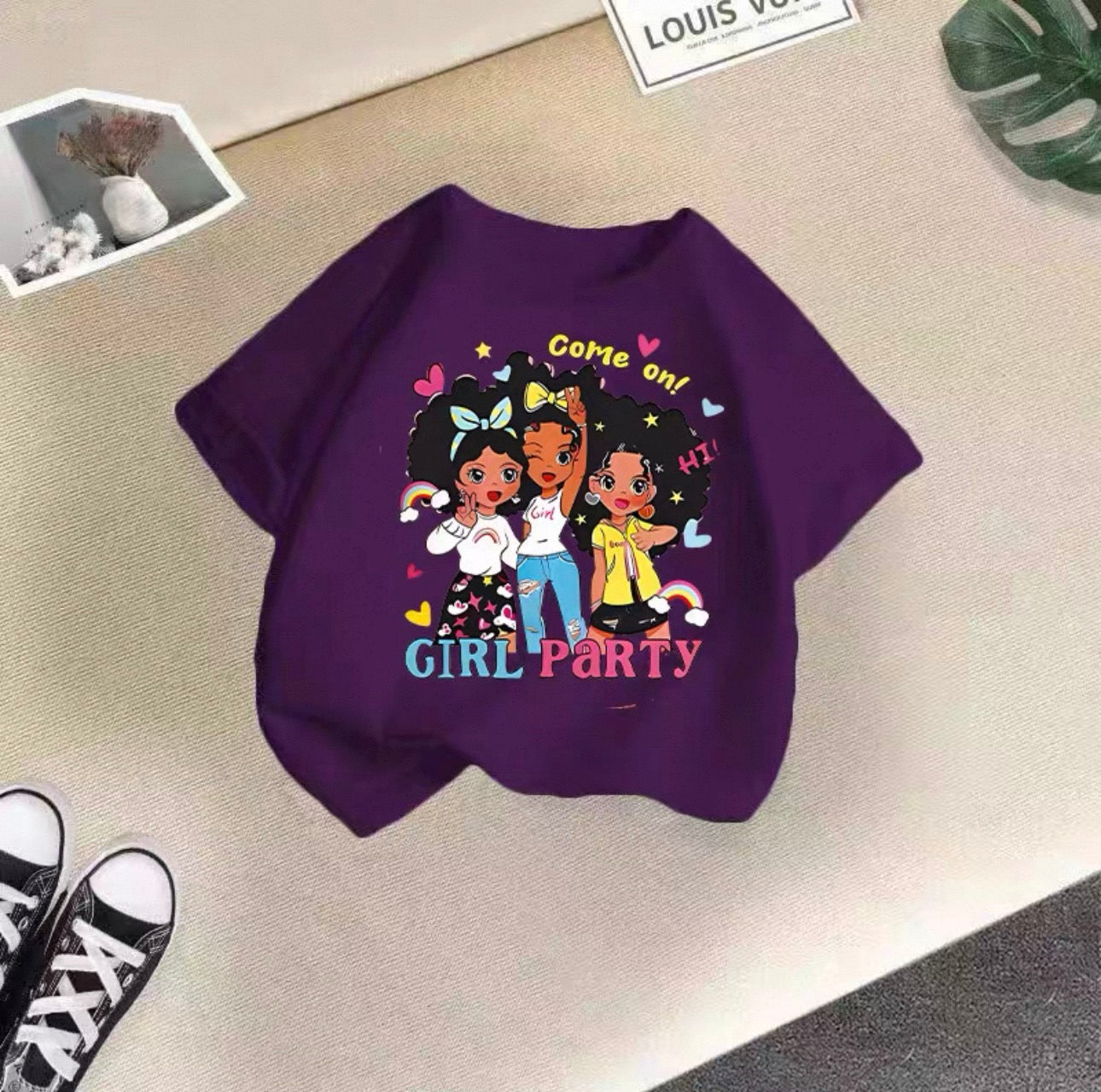 Purple sweatshirt with cartoon characters and text on a beige surface