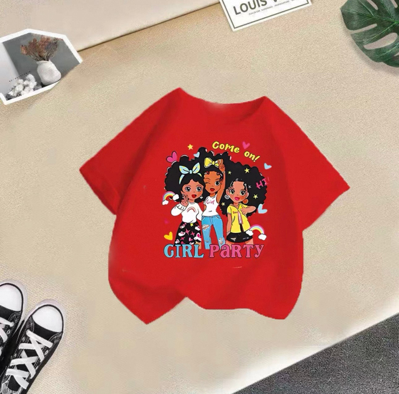 Red t-shirt with cartoon girls and text on a beige surface
