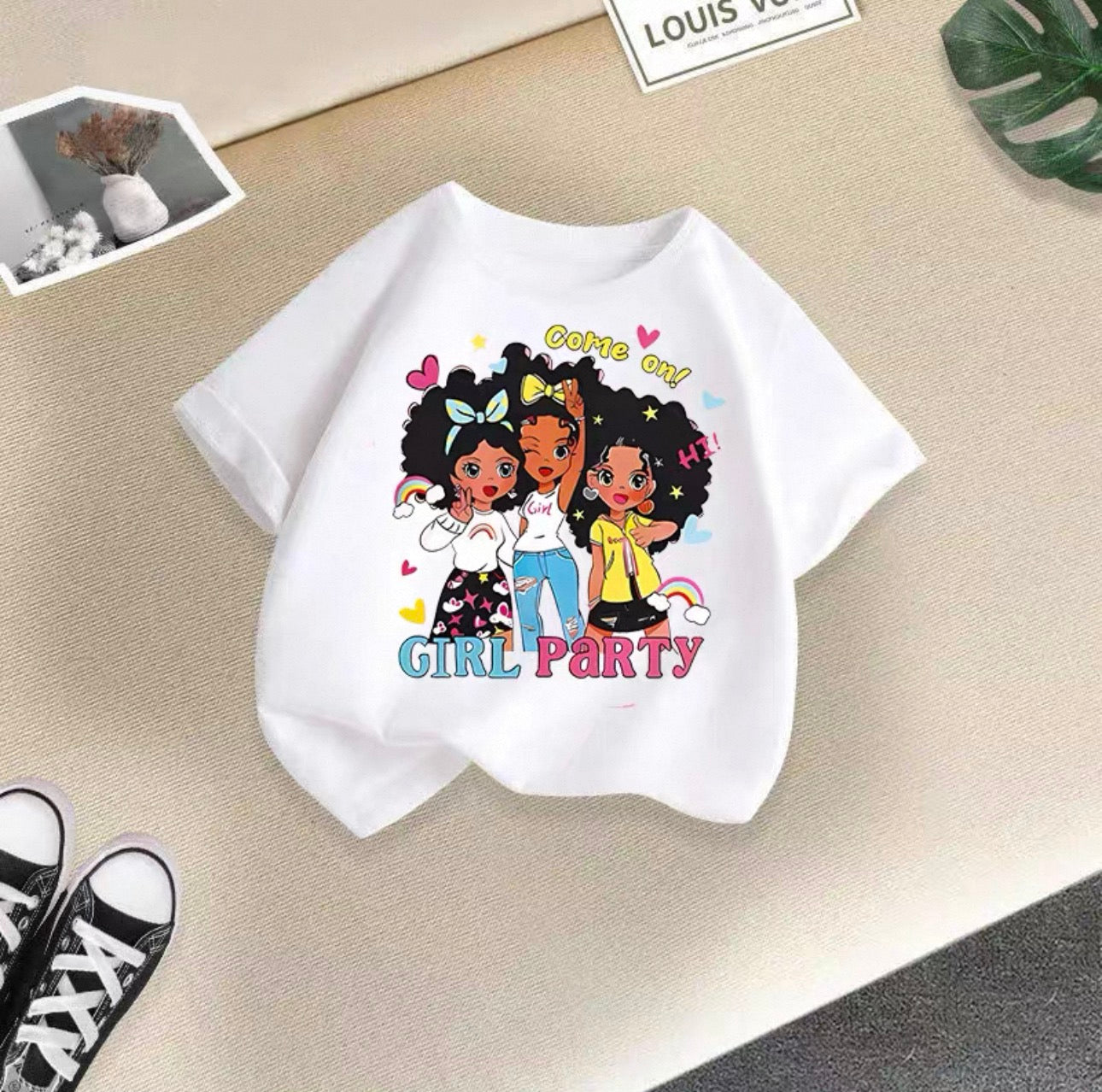 White t-shirt with cartoon girls and 'Girl Party' text on a beige surface.
