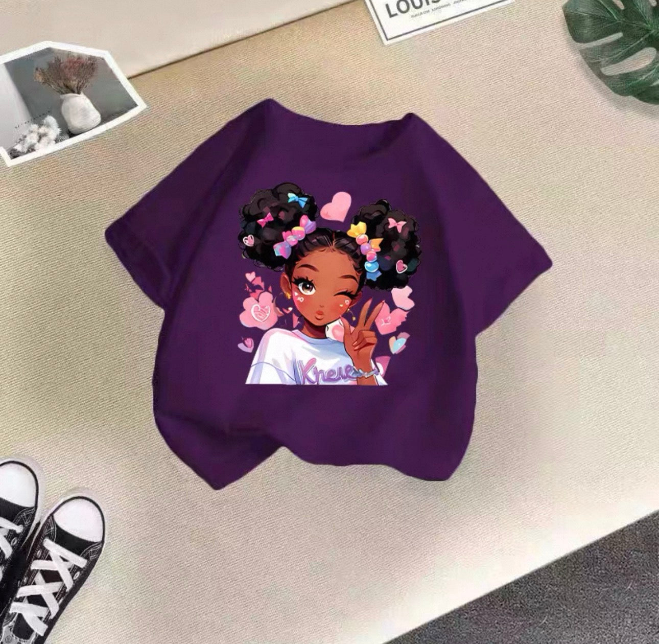 Purple sweatshirt with a graphic of a girl with flowers in her hair on a beige surface.