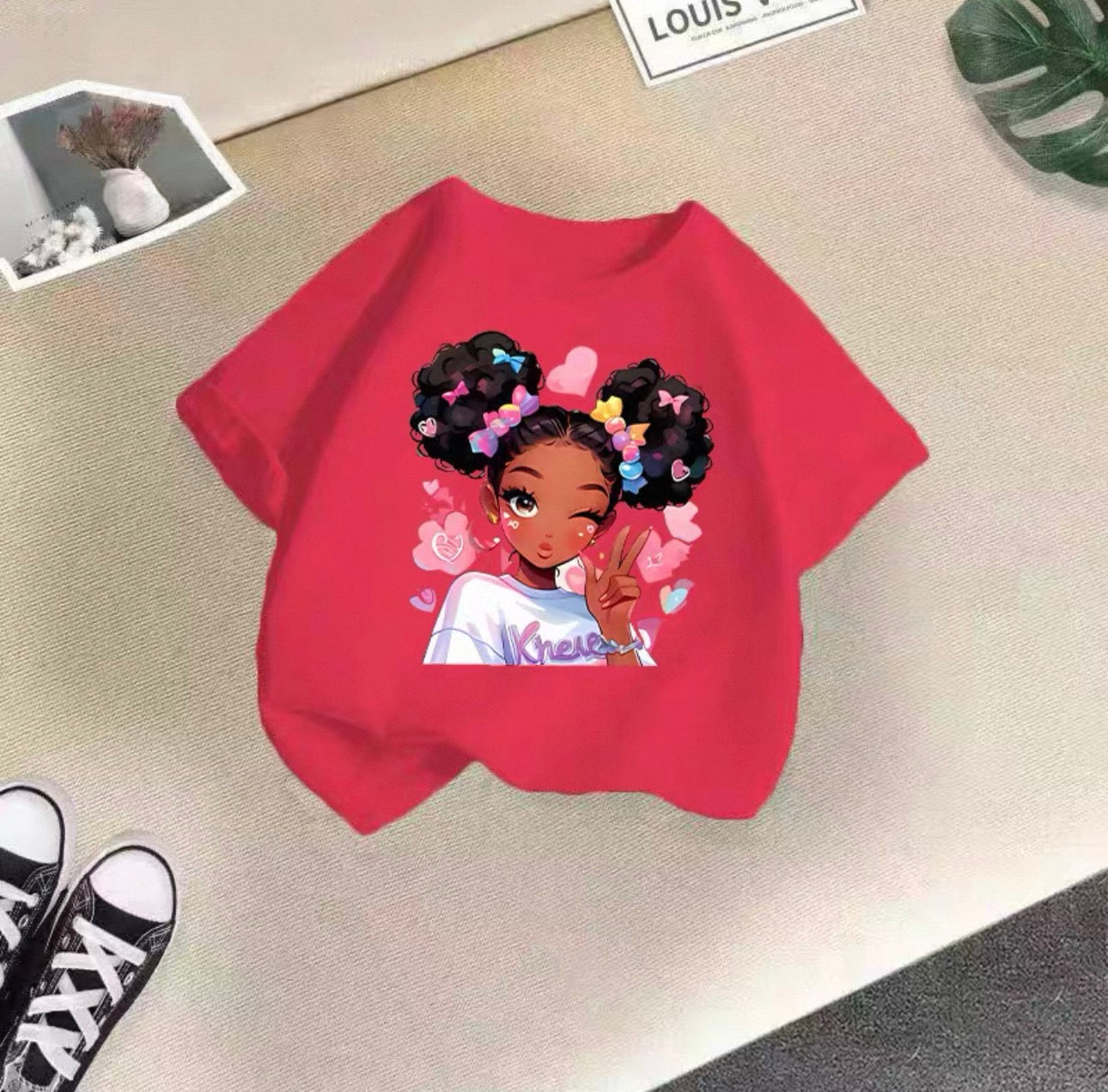 Red sweatshirt with a graphic of a girl with colorful hair on a beige surface.