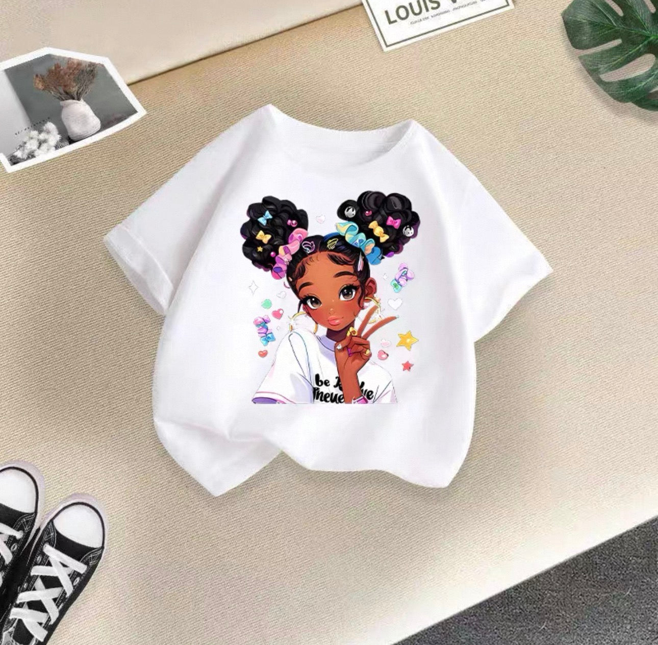 White t-shirt with a graphic of a girl with braids on a beige surface.