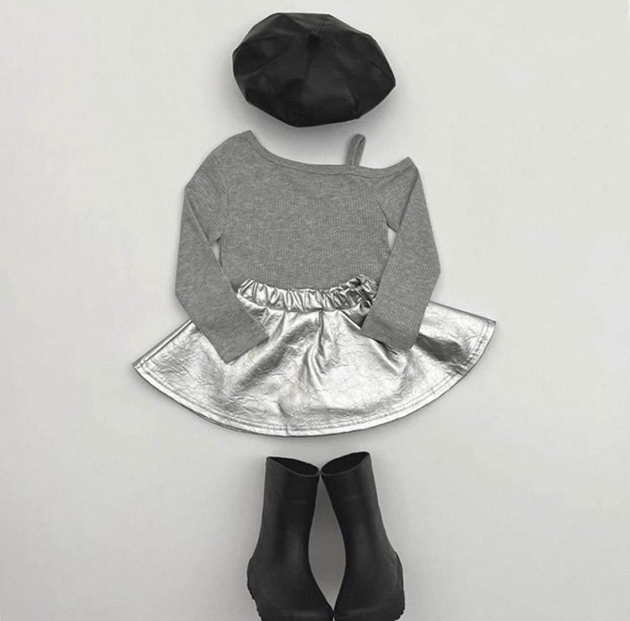 Gray long-sleeve top with silver skirt, black beret, and black ankle boots on a light gray background