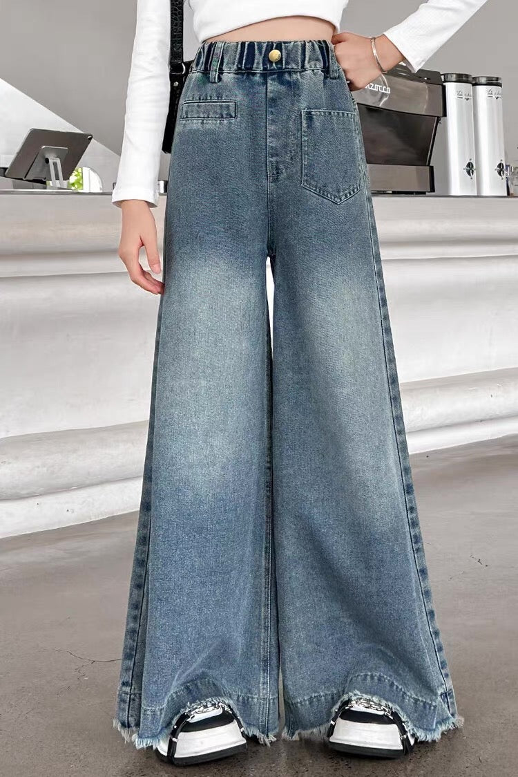 Person wearing high-waisted blue jeans with a blurred indoor background