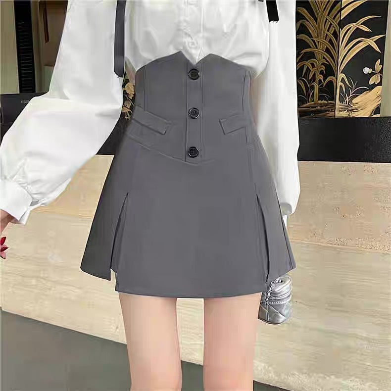 Person wearing a gray pleated skirt with a white blouse indoors.