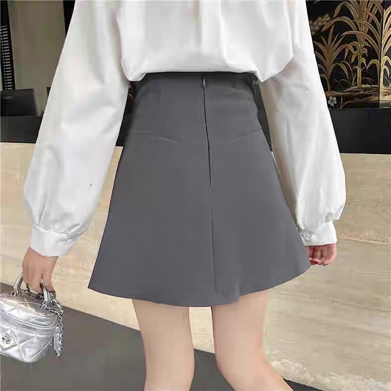 Person wearing a white blouse and gray skirt with a blurred background