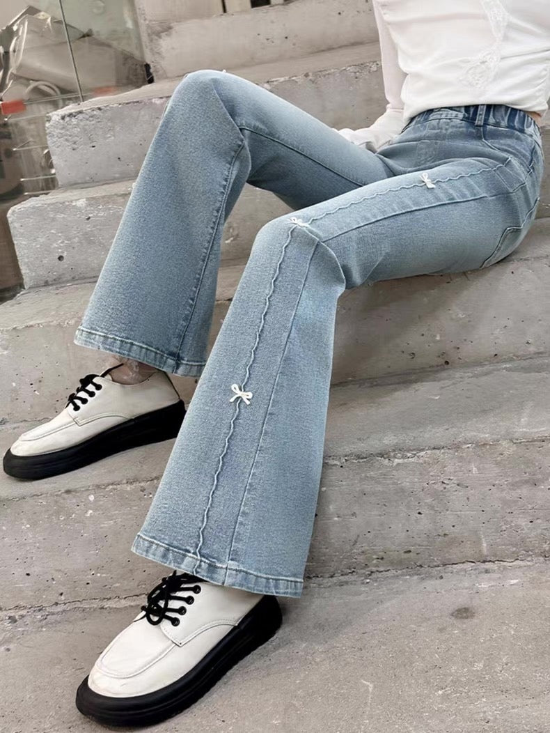 Person wearing light blue jeans and white sneakers with black soles on a concrete surface.
