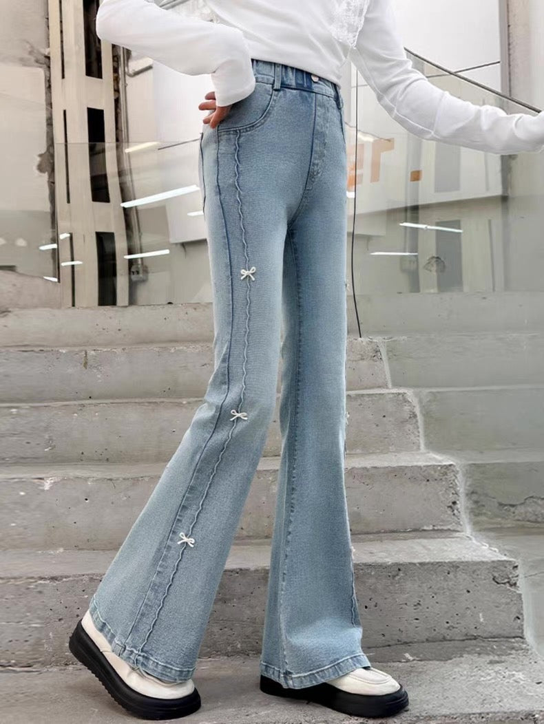 Person wearing light blue flared jeans standing on steps with a blurred background