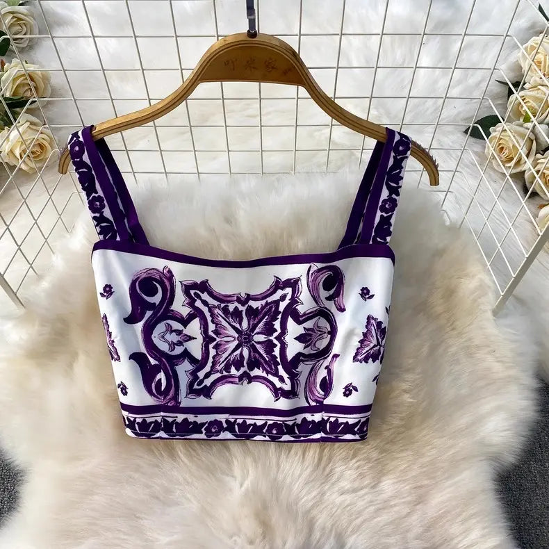 White top with purple floral patterns on a wooden hanger against a white grid background.