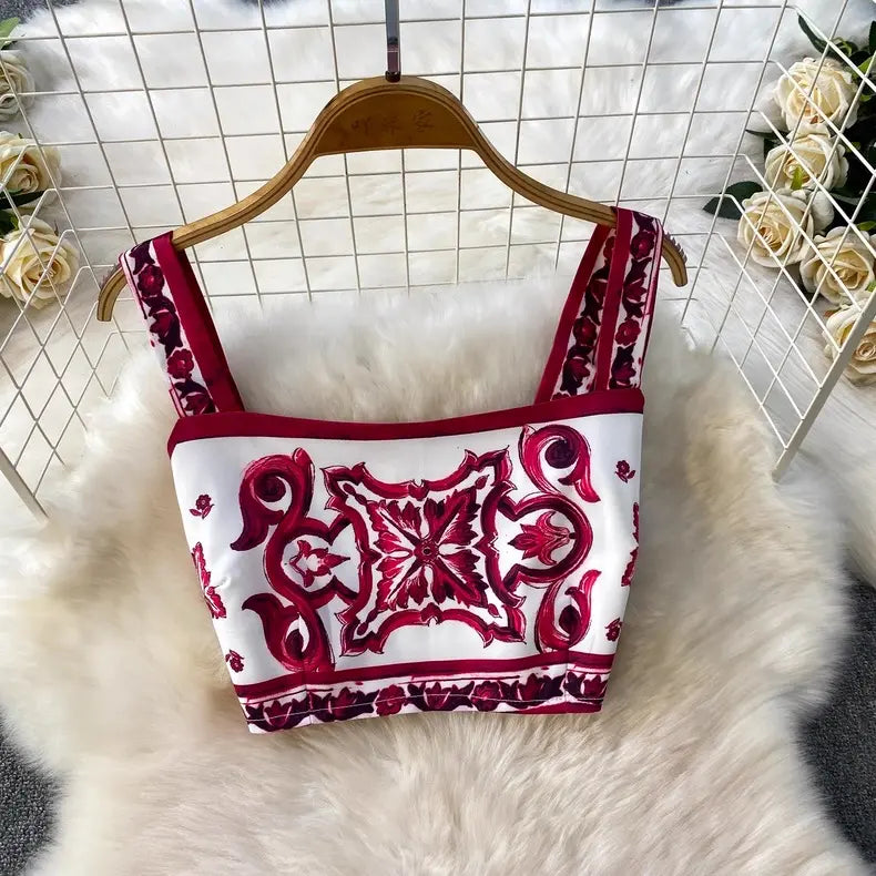 White top with red patterns on a hanger against a white grid background