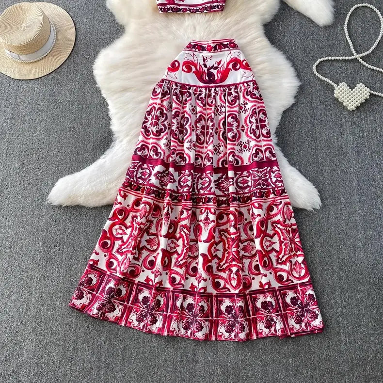 Red and white patterned dress on a gray surface with a hat and heart-shaped object.