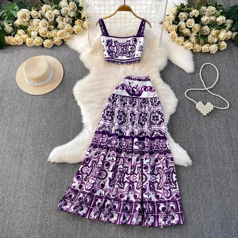 Purple patterned dress with matching top on a white fur rug, surrounded by flowers and a hat.