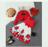 Red top and floral skirt set with accessories on a gray surface