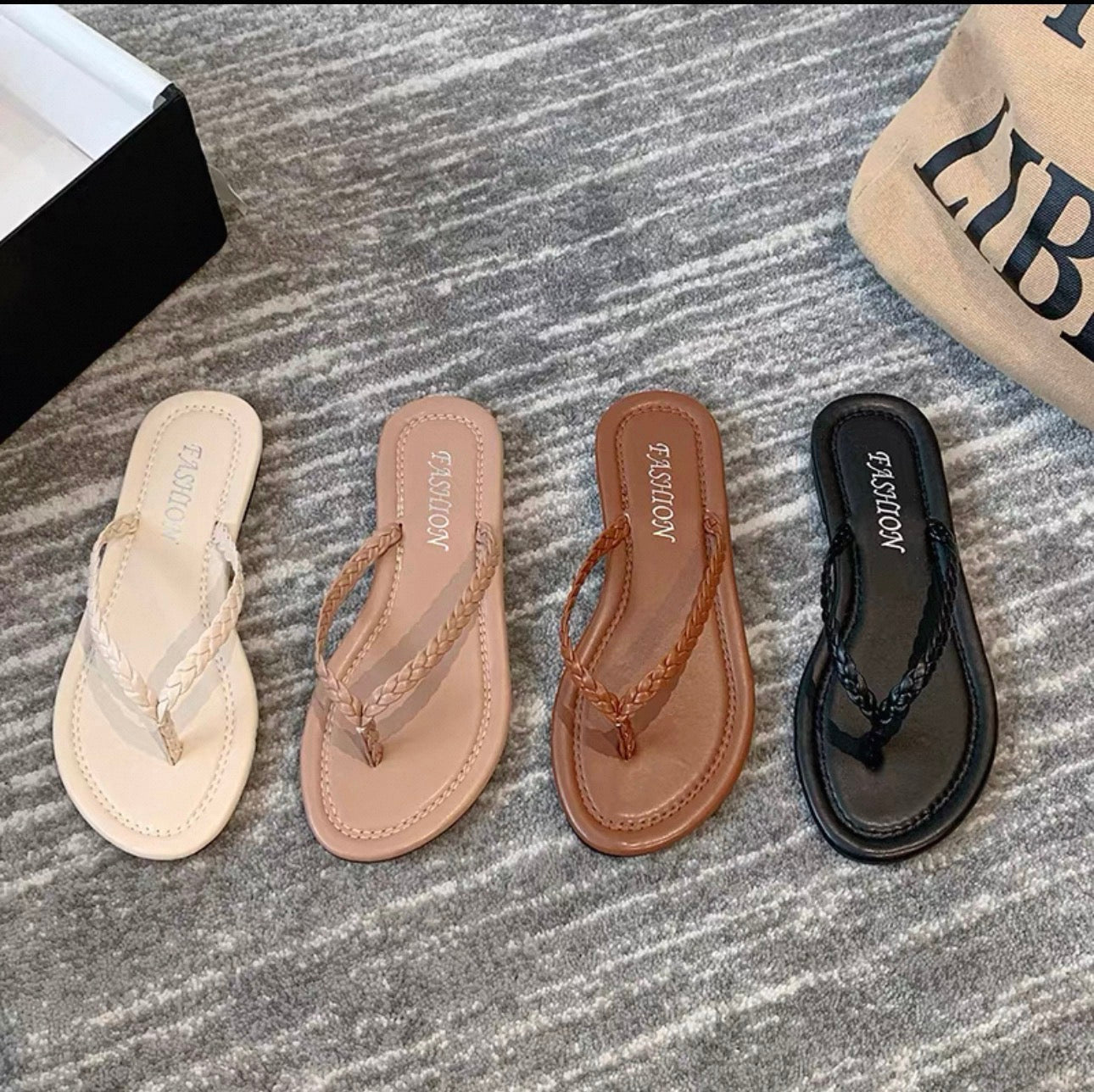 Four pairs of sandals in different colors on a textured surface.
